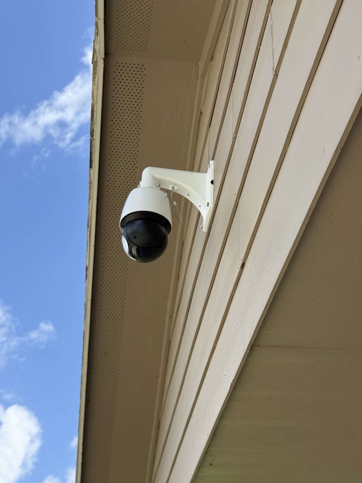 Fixed surveillance camera installed under a building eave.