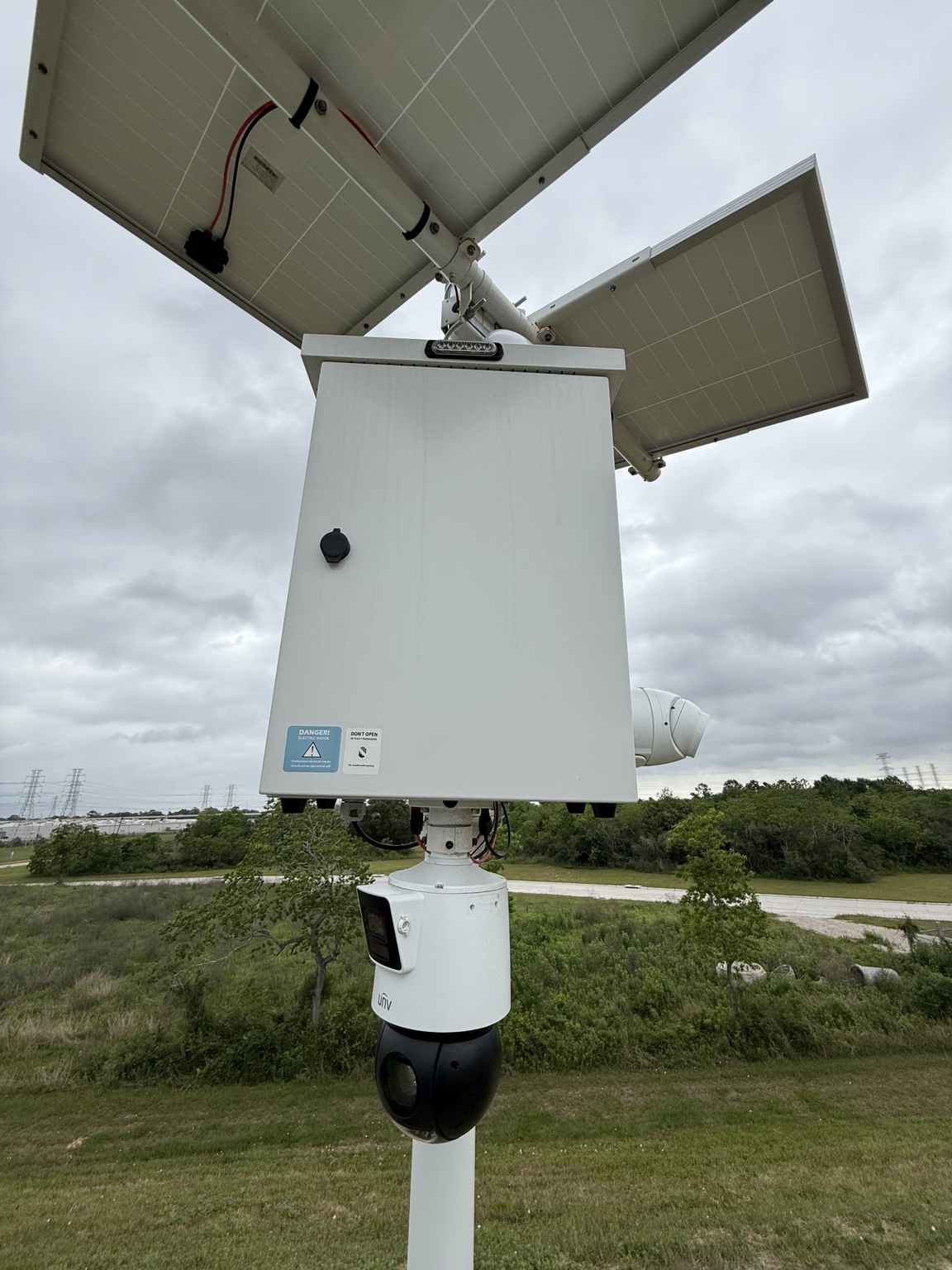 Off-grid camera pole with solar panels, an equipment enclosure, and a mounted camera.